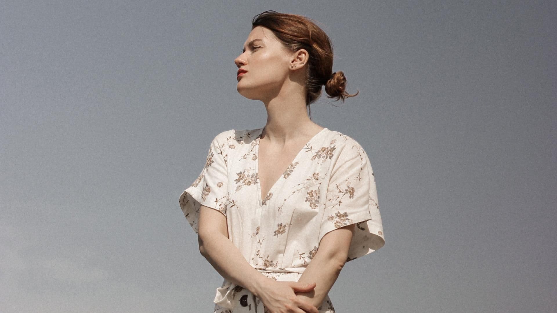 Mädchen im geblümten Kleid vor blauem Himmel