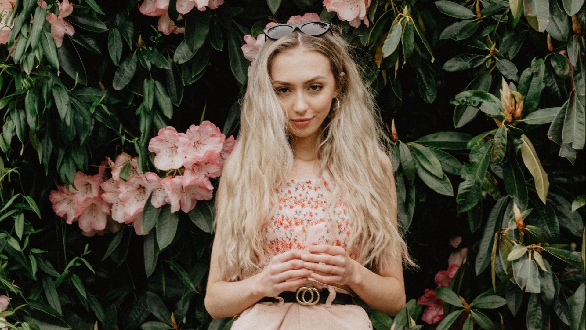 Mädchen blonde Haare vor Blumenbusch
