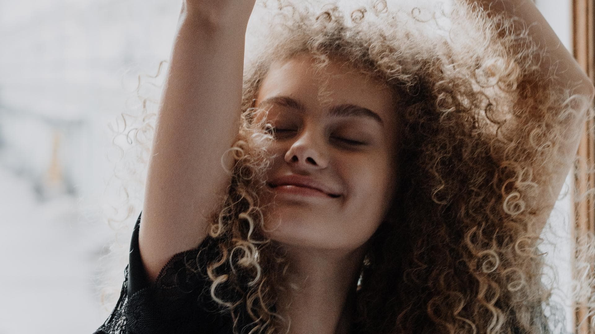 Mädchen mit Locken vor einem Fenster