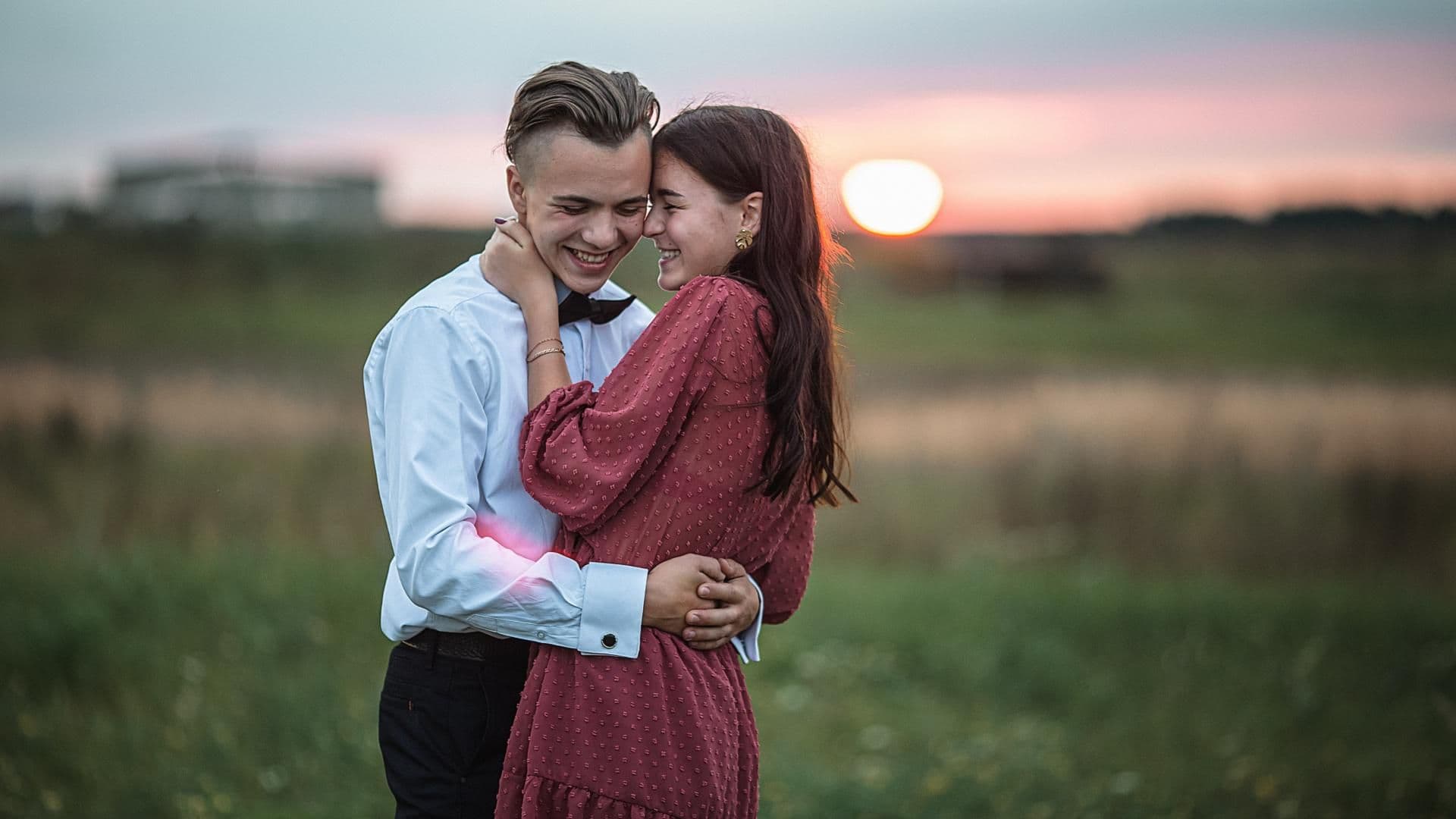 Mädchen und Junge umarmen sich auf einer Wiese