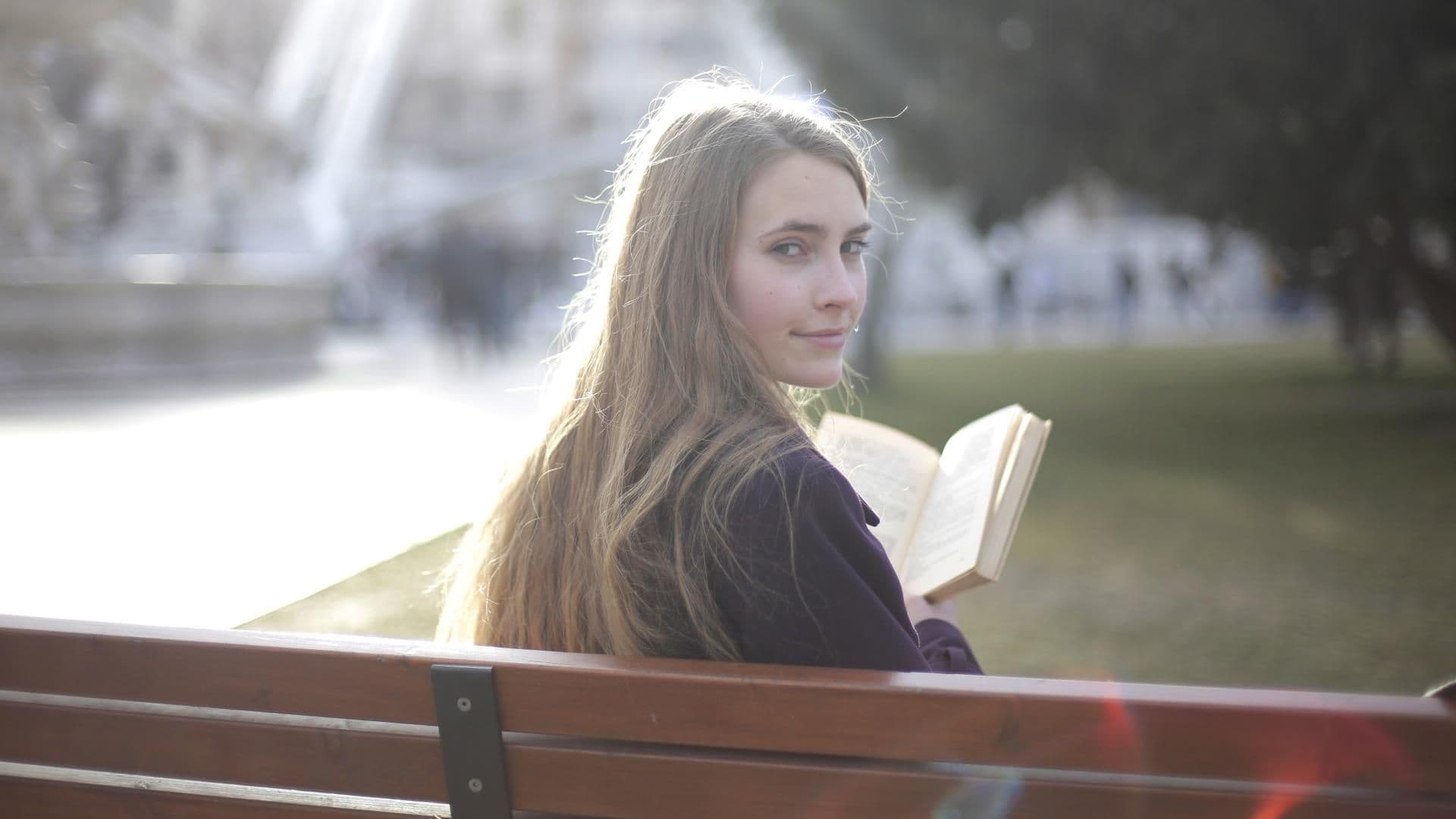 Mädchen auf einer Parkbank mit einem Buch