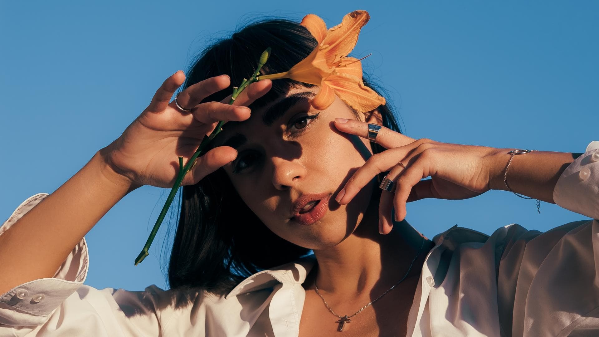 Mädchen vor blauem Himmel mit Blume in der Hand