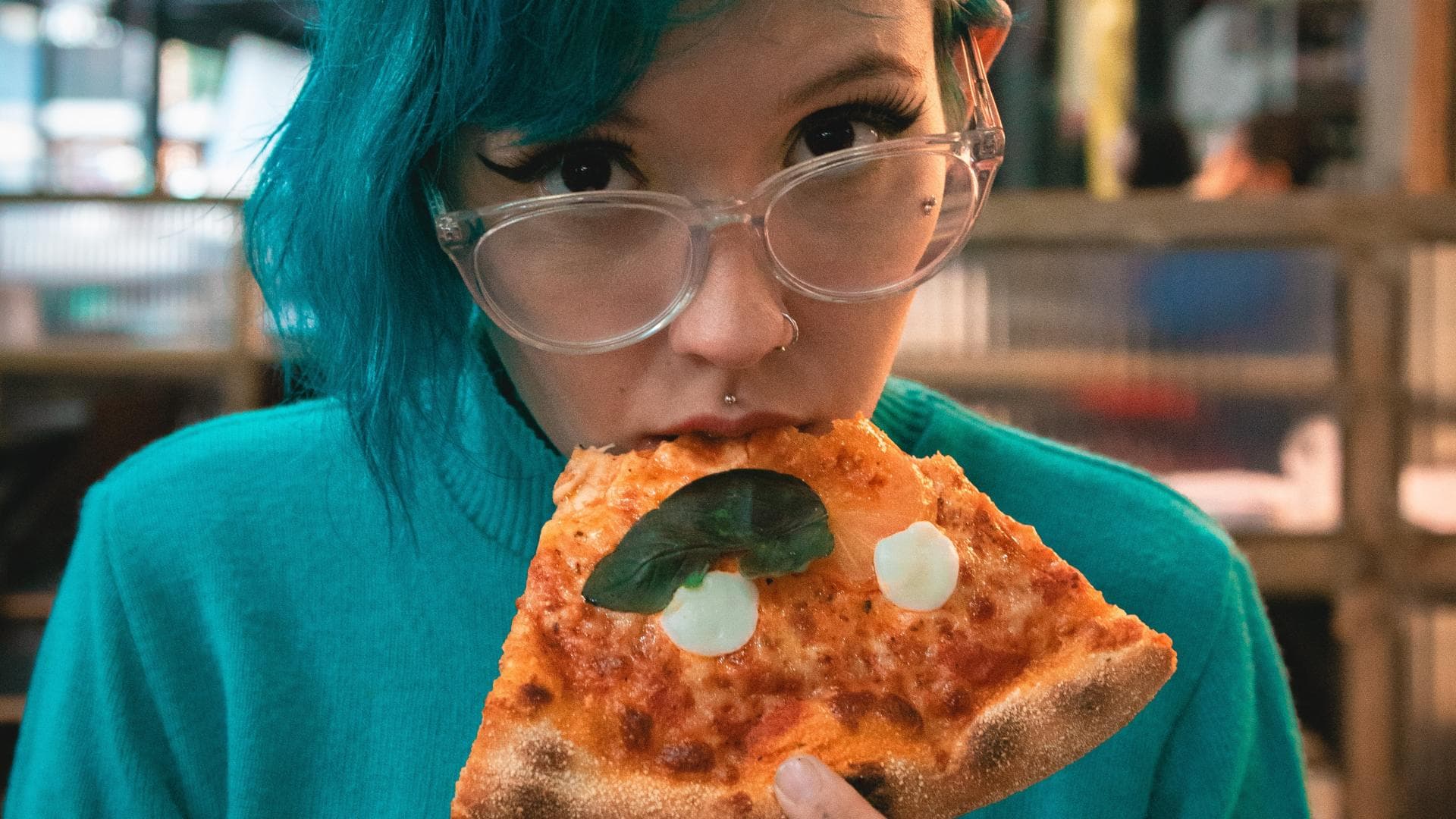 Mädchen mit blauen Haaren isst Pizza