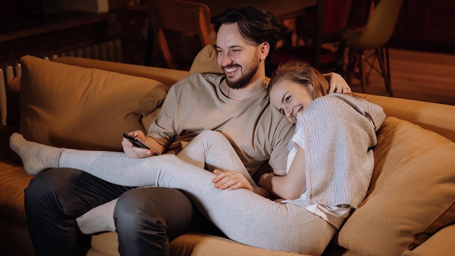 Mann und Frau sitzen auf der Couch und lachen