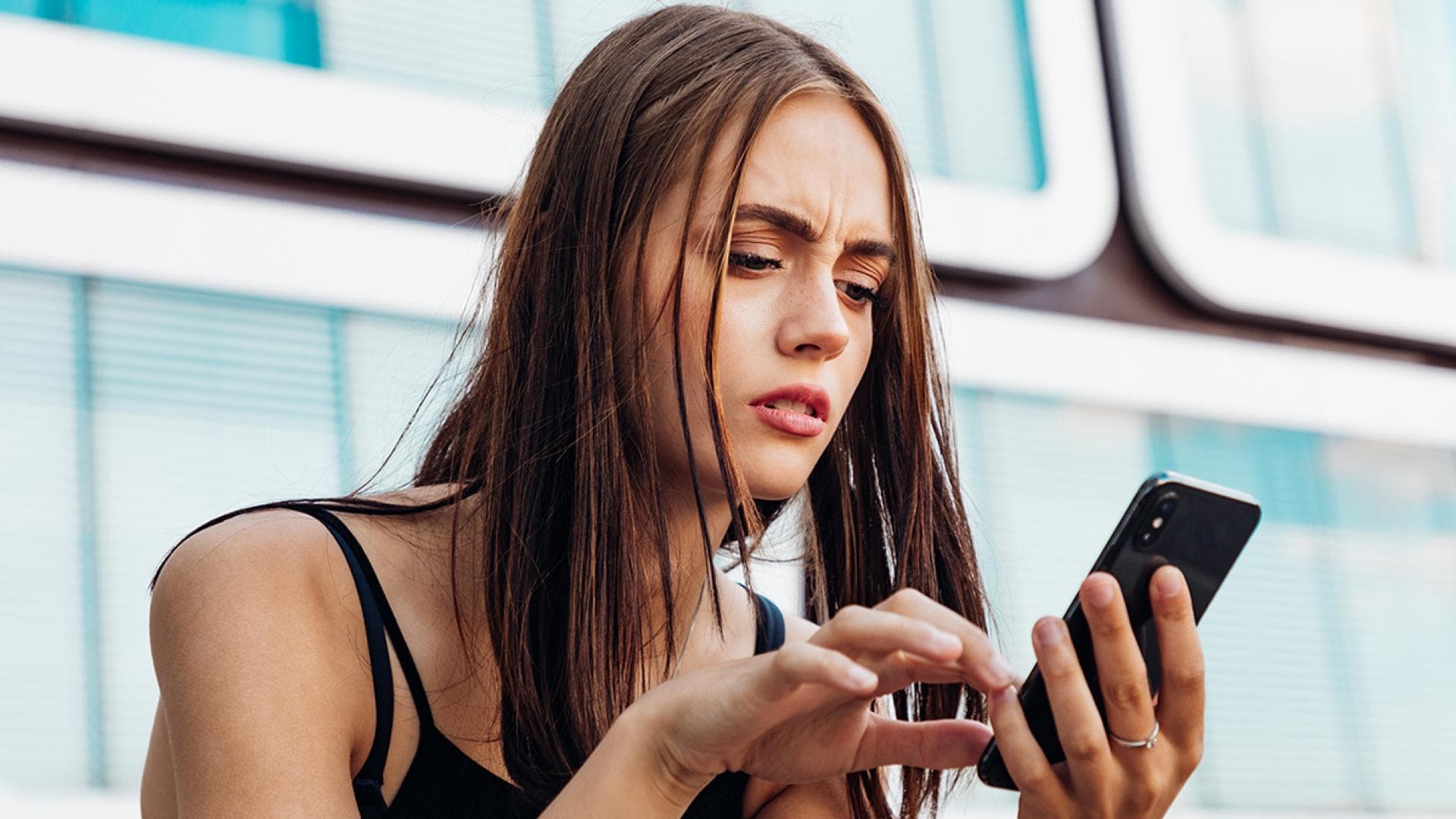 Frau schaut verwirrt auf Handy
