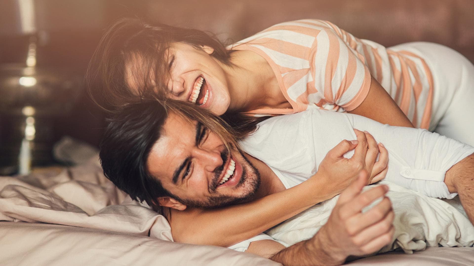 Mann und Frau umarmen sind lachend auf einem Bett