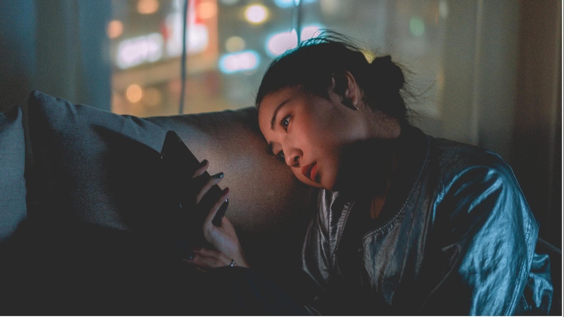 Eine Frau schaut müde auf ihr Handy