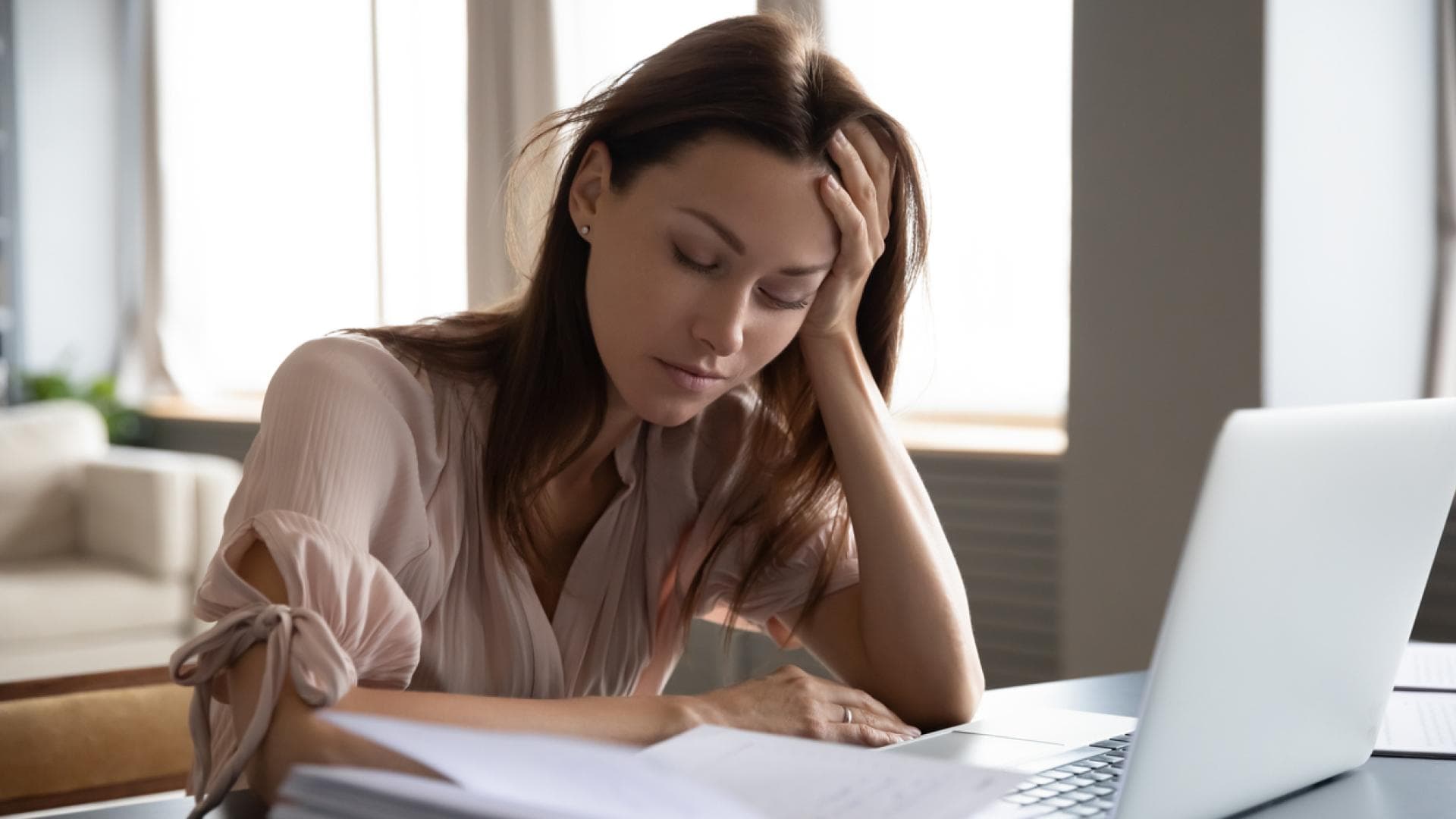 Junge Frau sitzt müde vor einem Laptop