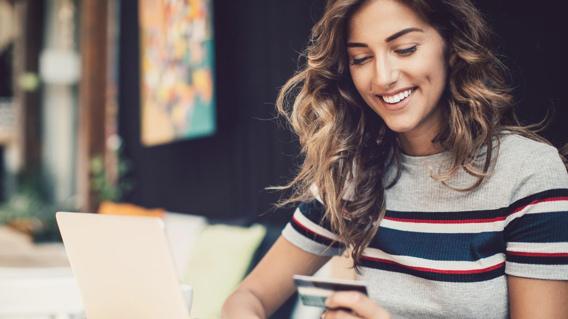 Eine Frau sitzt mit ihrer Bankkarte vor dem Laptop