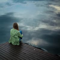 Mobbing in der Schule: Das kannst du dagegen tun Mädchen sitzt allein auf einem Steg