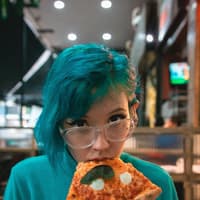 Mädchen mit blauen Haaren isst Pizza