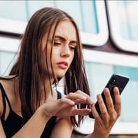 Frau schaut verwirrt auf Handy