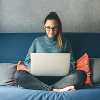 Junge Frau sitzt auf dem Sofa mit Laptop