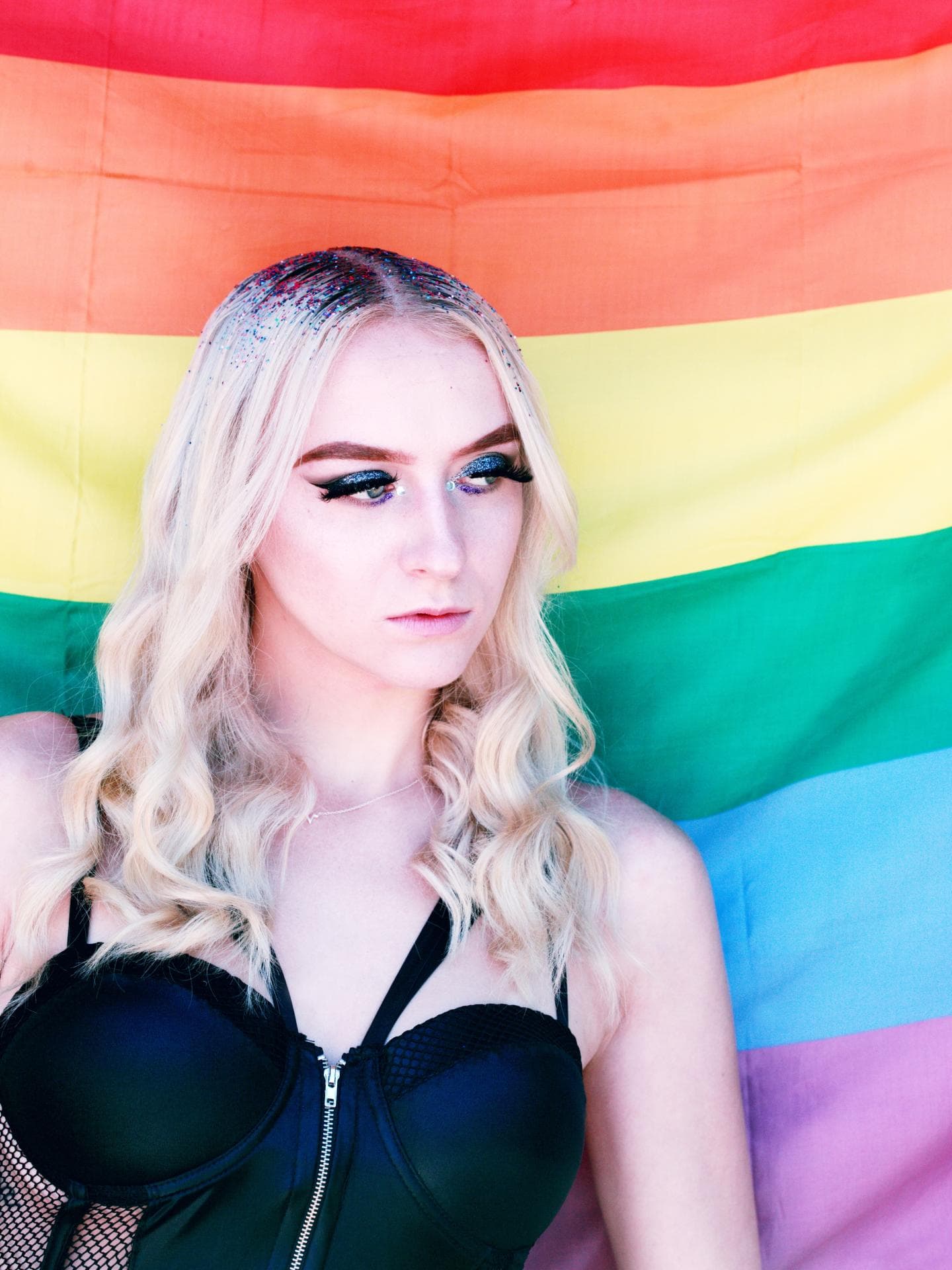 Blonde Person vor Regenbogen Flagge