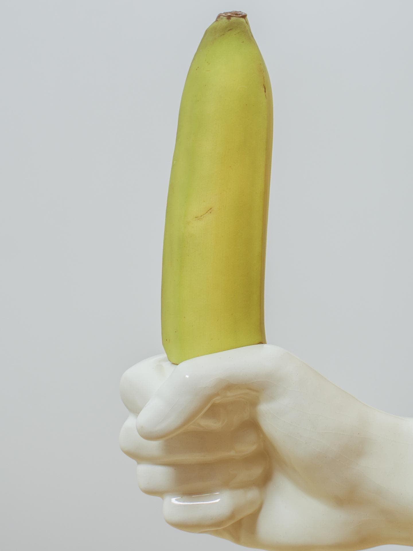 Porzellanhand, die eine Banane greift