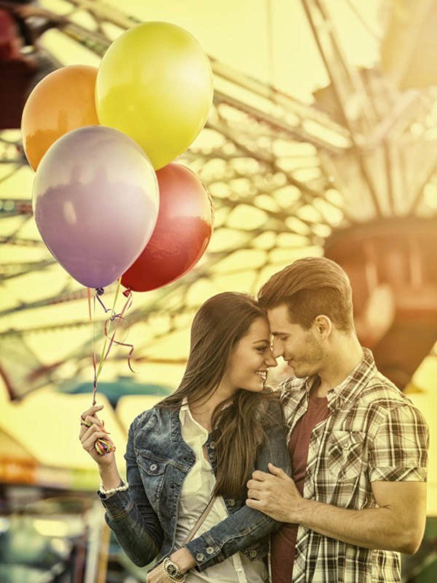 Mädchen und Junge vor Riesenrad mit Luftballons