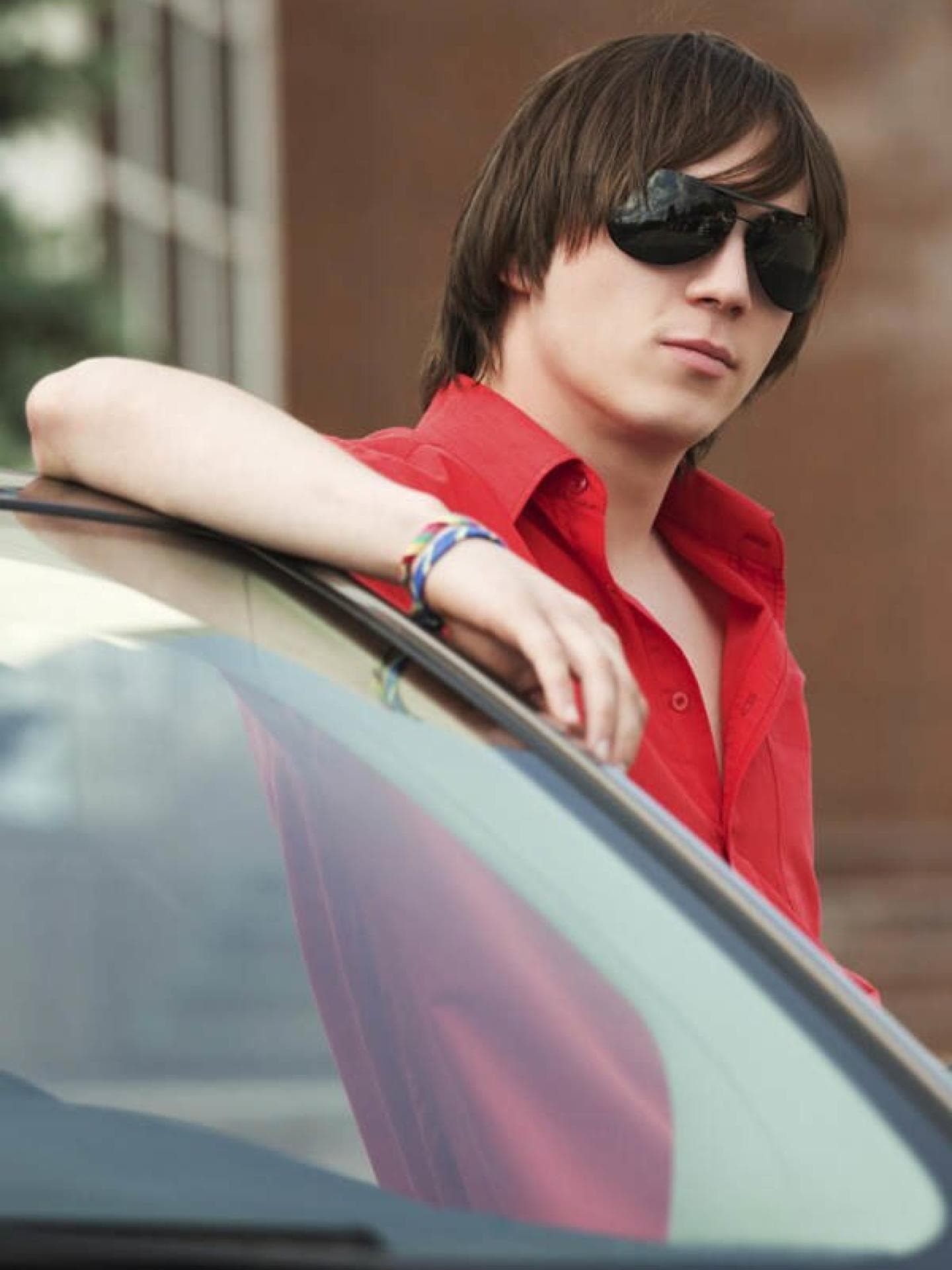 Junge mit Sonnenbrille an Auto gelehnt