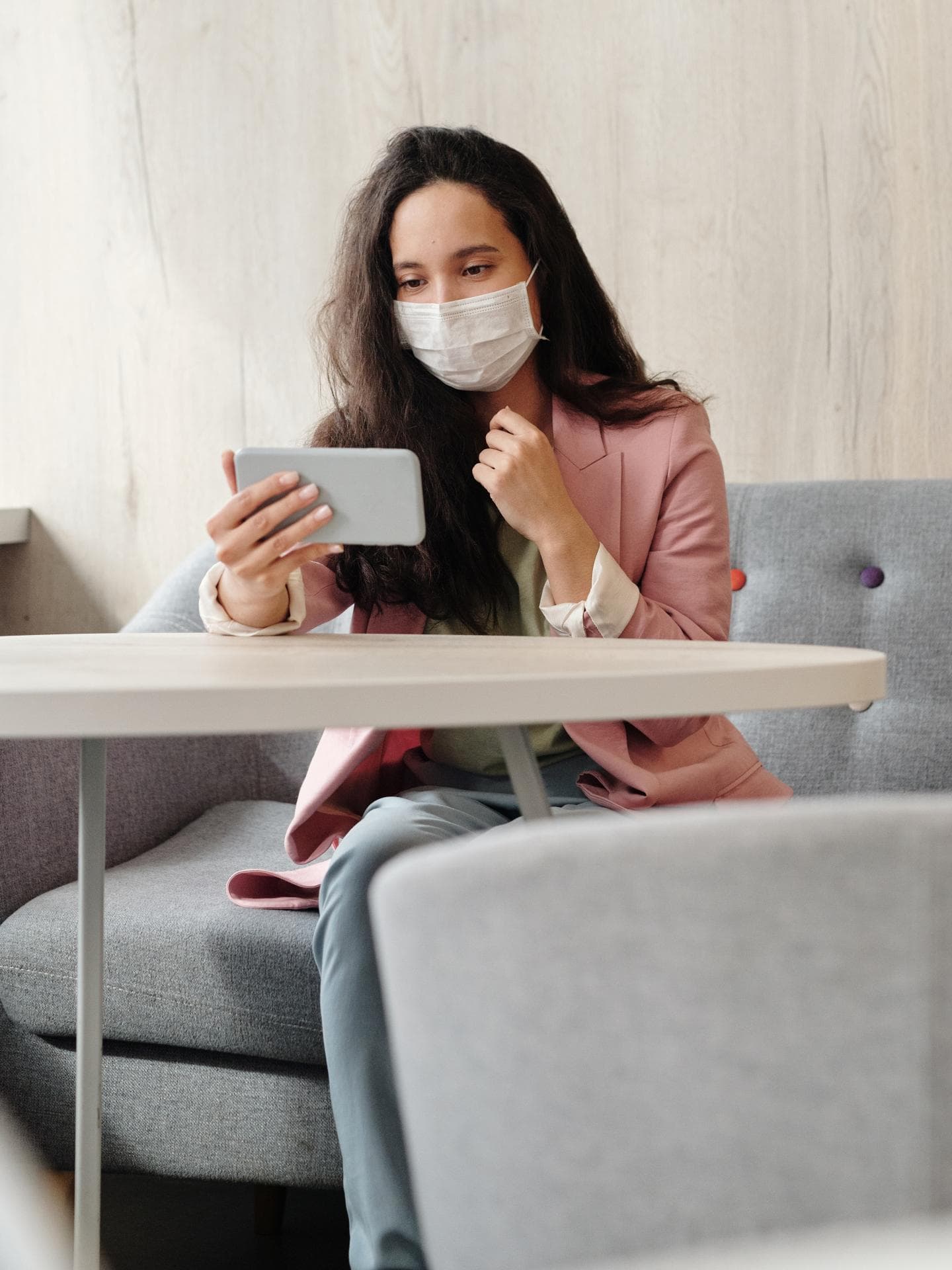 Frau mit Maske sitzt an einem Tisch