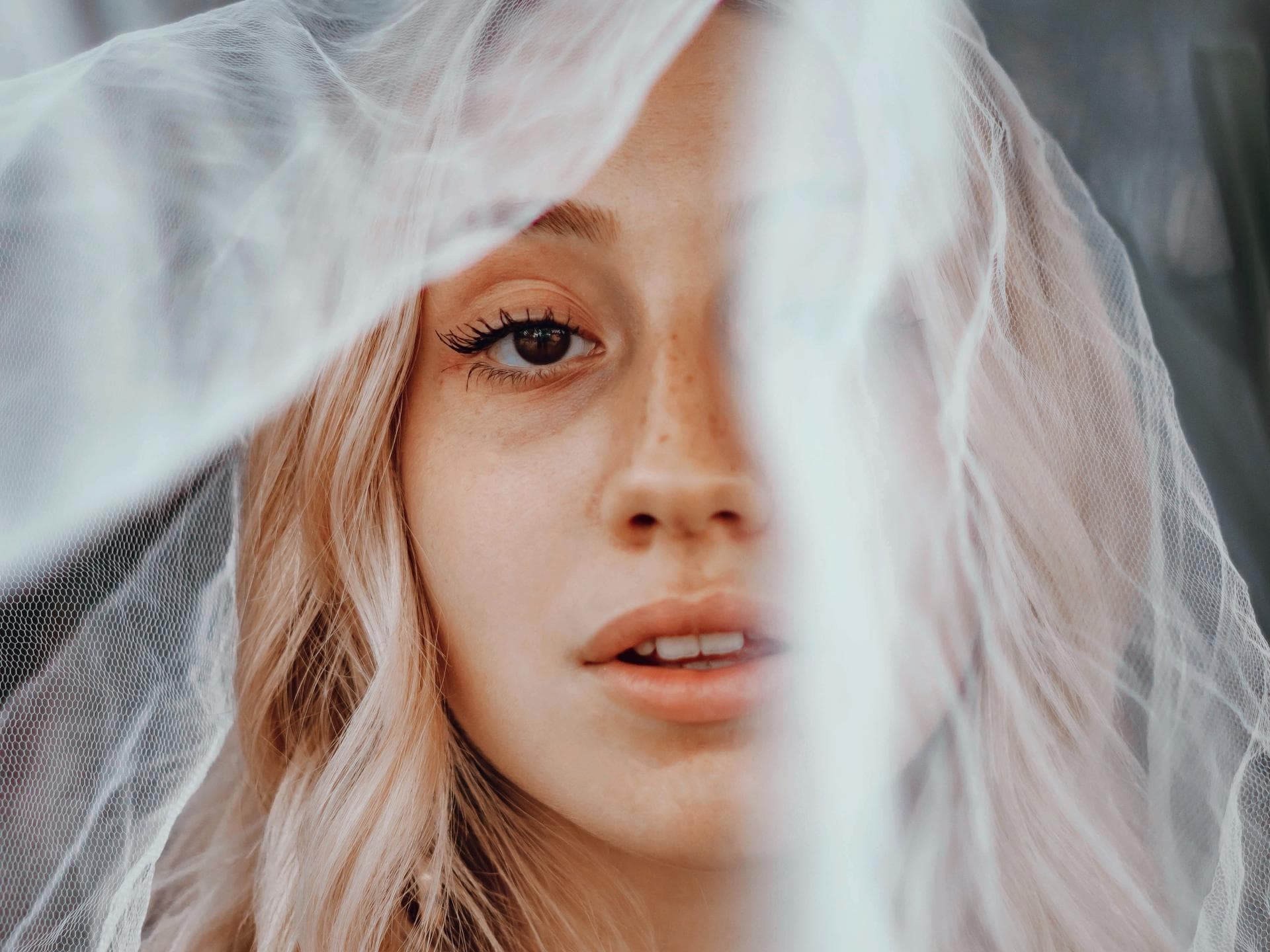 Wochen-Horoskop Blondes Mädchen mit weißem Schleier vorm Gesicht