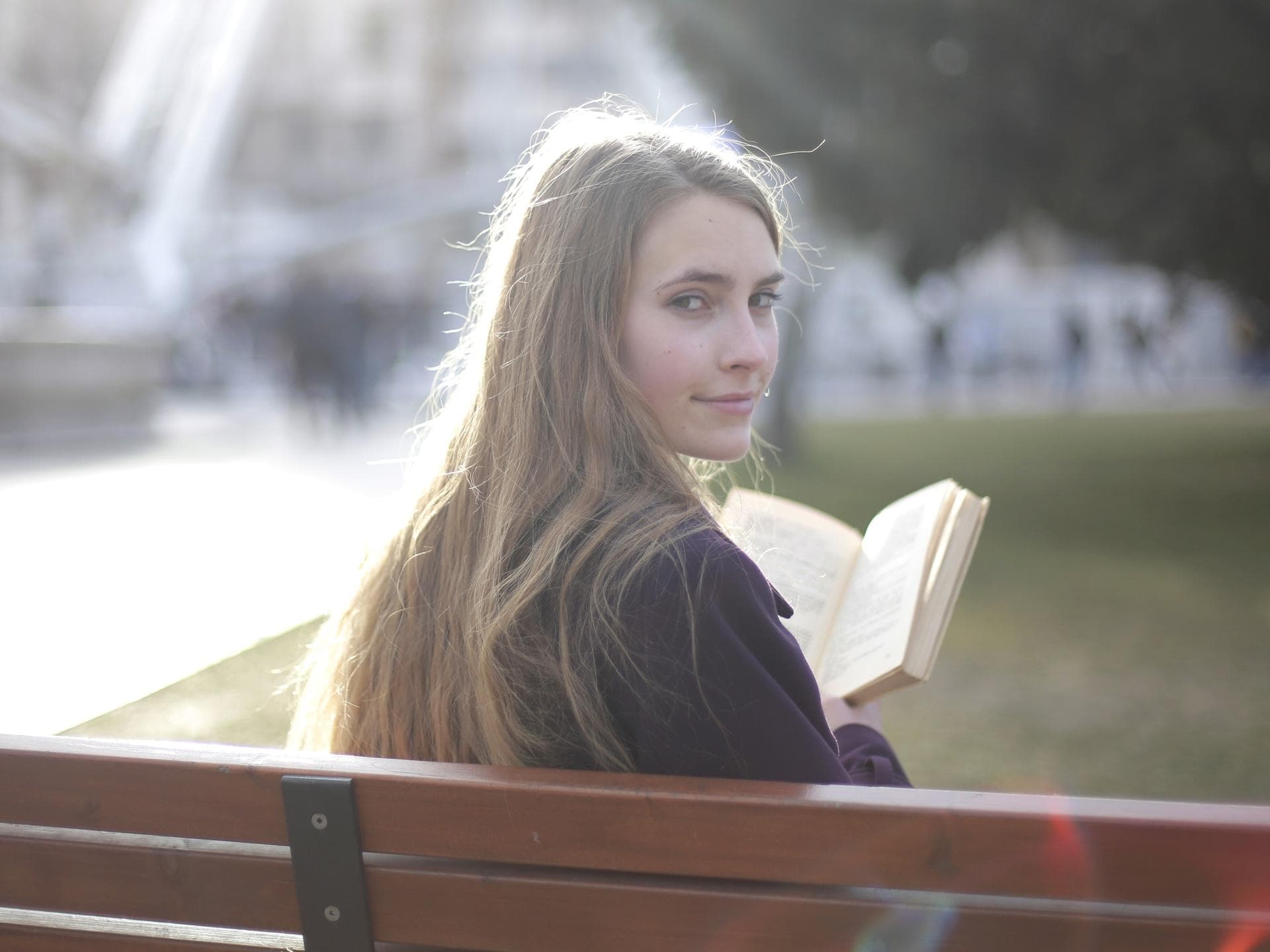 Referat halten Mädchen auf einer Parkbank mit einem Buch