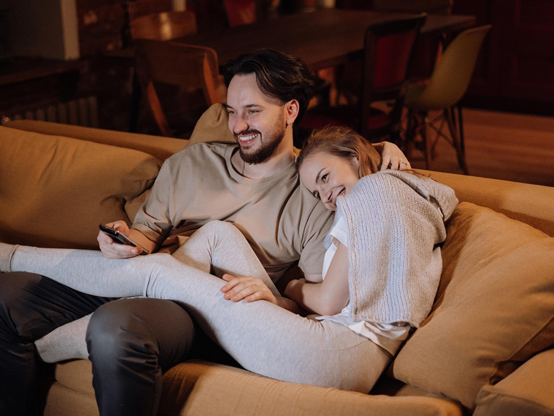 Mann und Frau sitzen auf der Couch und lachen