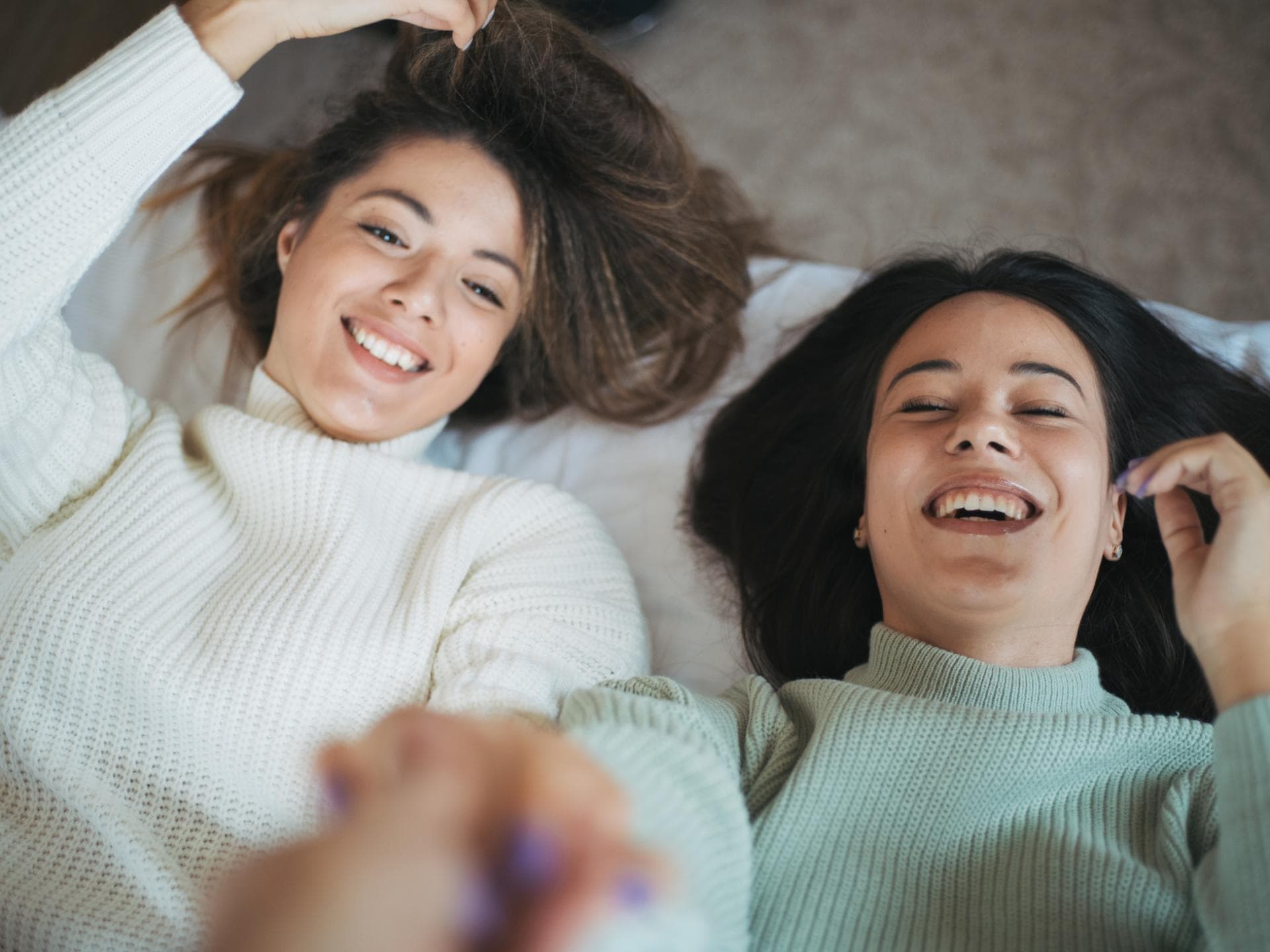 Zwei Freundinnen liegen im Bett und lachen
