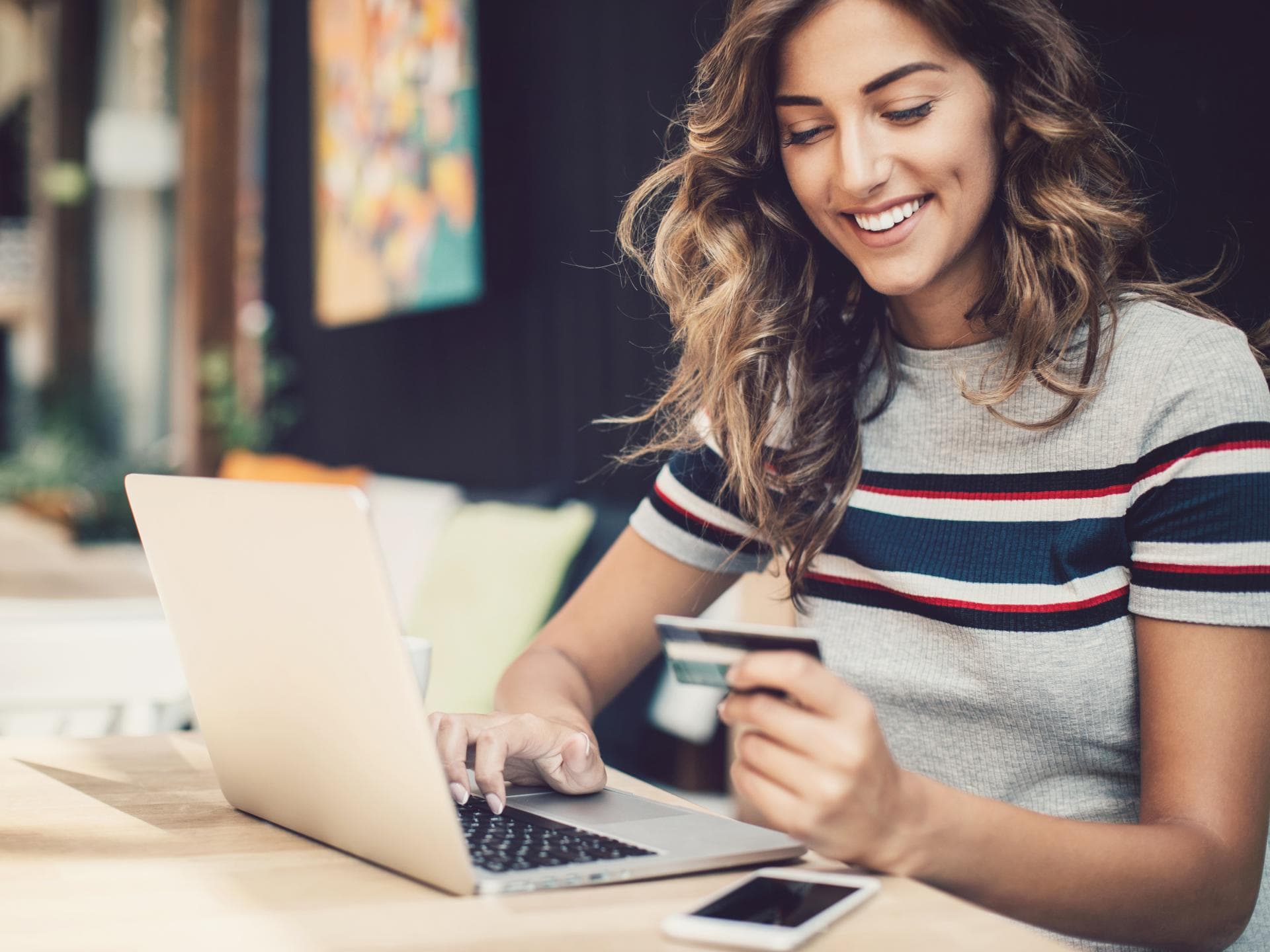 Eine Frau sitzt mit ihrer Bankkarte vor dem Laptop