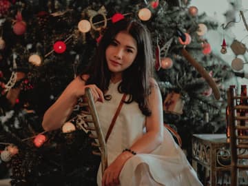 Mädchen im weißen Kleid vor Weihnachtsbaum