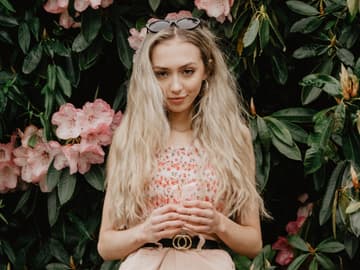 Mädchen mit blonden Haaren vor Blumenwand