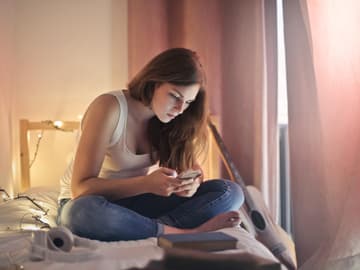 Mädchen mit Handy im Bett
