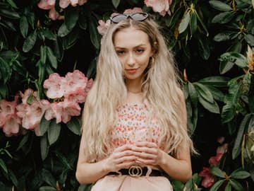 Mädchen blonde Haare vor Blumenbusch