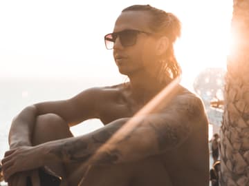 Junge sitzt in der Sonne am Meer