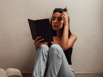 Mädchen sitzt auf dem Boden mit Büchern