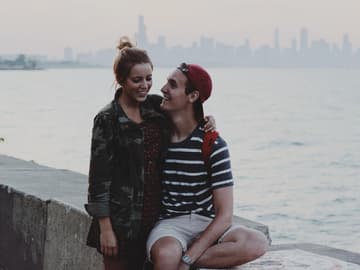 Mädchen und Junge auf einer Mauer vor einem See
