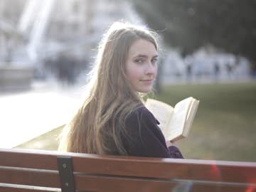 Mädchen auf einer Parkbank mit einem Buch