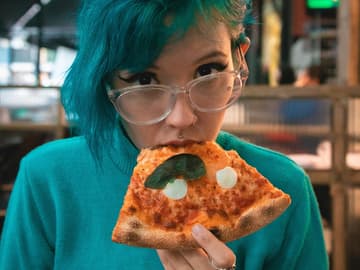 Mädchen mit blauen Haaren isst Pizza