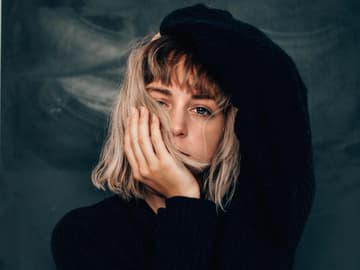Blondes Mädchen mit Händen im Gesicht und am Kopf