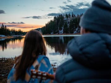 Mädchen und Junge mit Gitarre am See