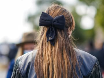 Frau mit brünettem Haar und großer Schleife von hinten