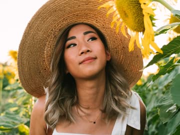 Horoskop der Woche: Junge Frau mit Sonnenblumen und Hut