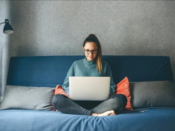 Junge Frau sitzt auf dem Sofa mit Laptop