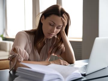 Junge Frau sitzt müde vor einem Laptop