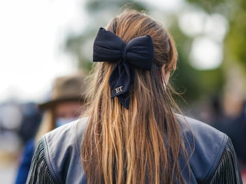 Haar Trends 2021 Frau mit brünettem Haar und großer Schleife von hinten