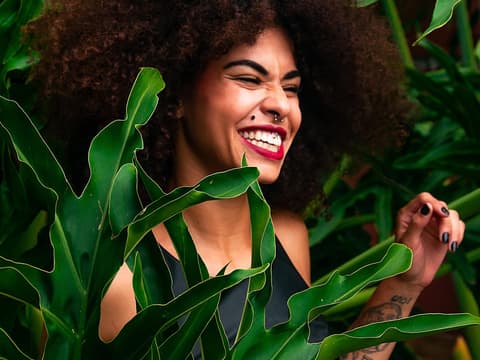 Horoskop der Woche: Frau steht in Pflanzen und lacht