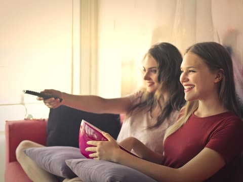 Netflix Romantische Komödien Zwei Freundinnen auf dem Sofa beim Filme schauen
